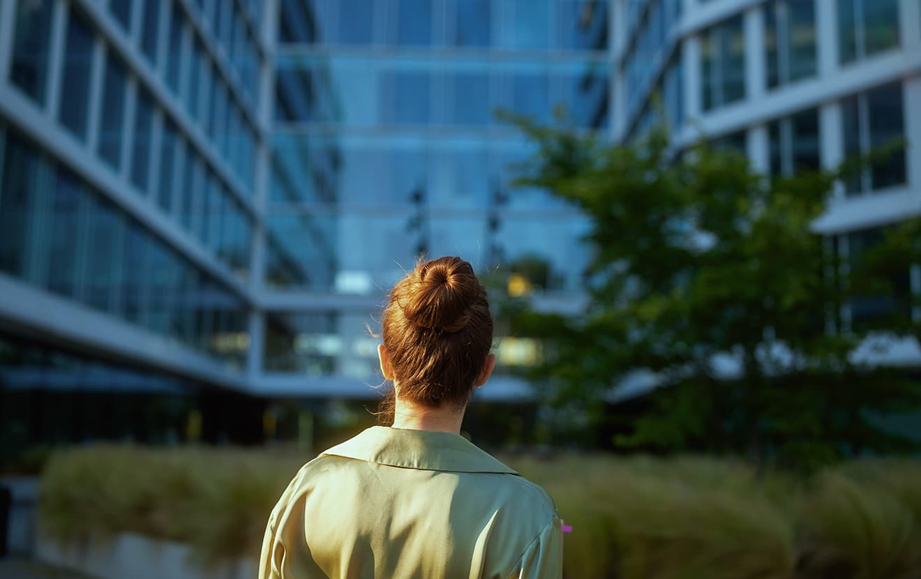 woman standing in front of the office with green trees
