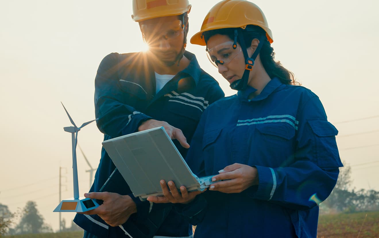 two wind powerplant workers looking at the laptop 