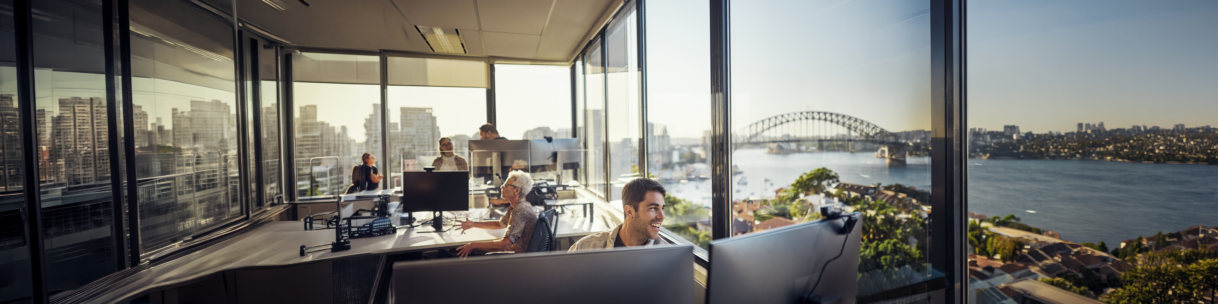 Man working at his desk in the office with a view on one of the Australians city skylines 