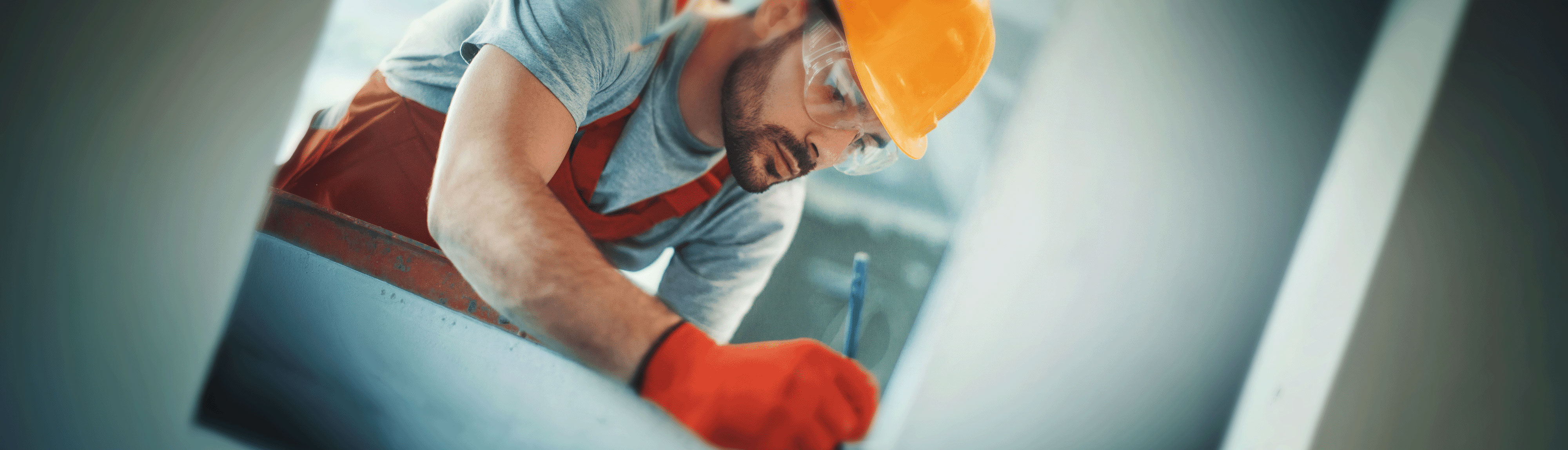 Male construction worker in safety gear taking measurements at a work site