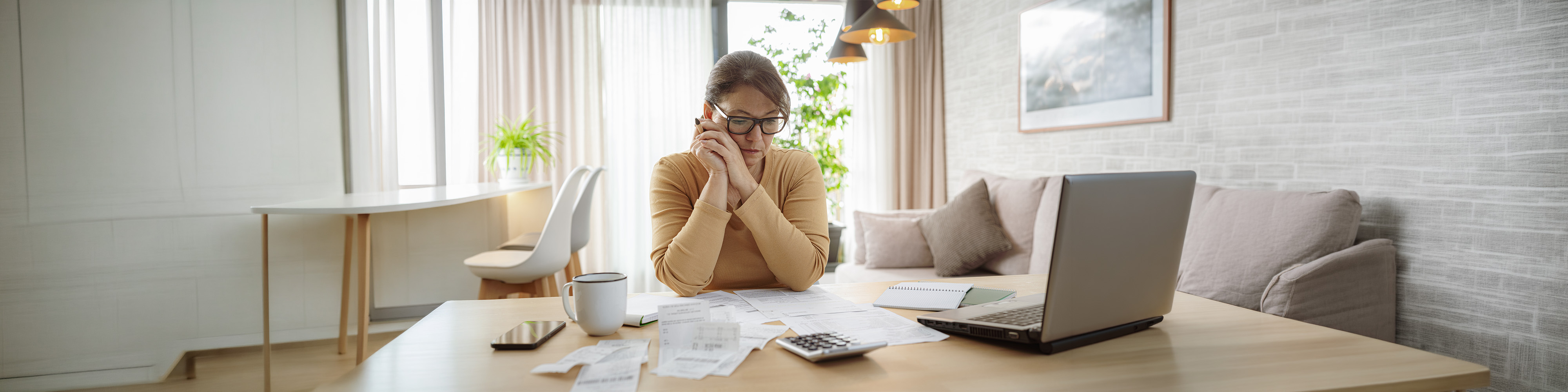 Mature woman contempling bills and tax papers at home